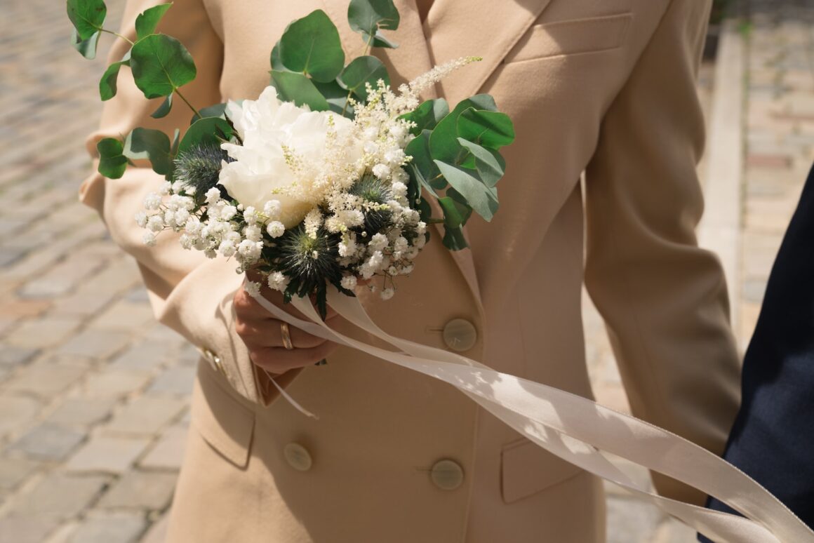 woman in beige blazer holding white flower bouquet - Trauzeugen Aufgaben und Pflichten