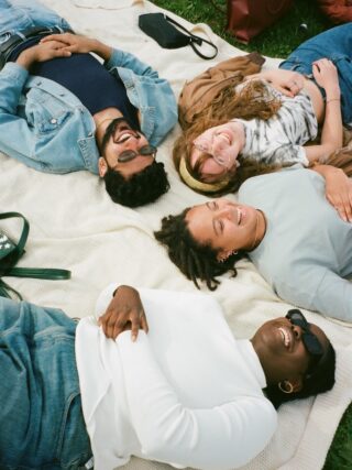 man in blue button up shirt lying on white bed - lustige fragen für freunde