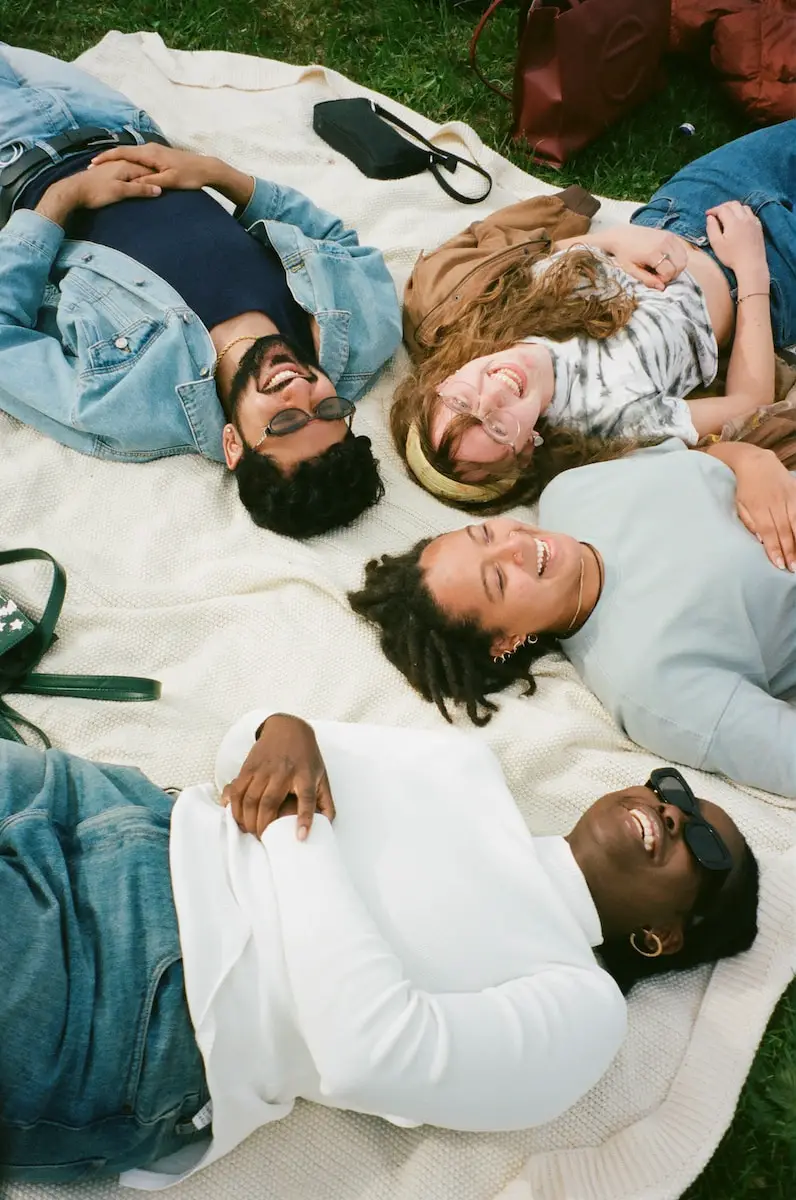 man in blue button up shirt lying on white bed - lustige fragen für freunde