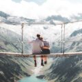 wochenendtrip zu zweit - minimoon - man and woman sitting on hanging bridge at daytime