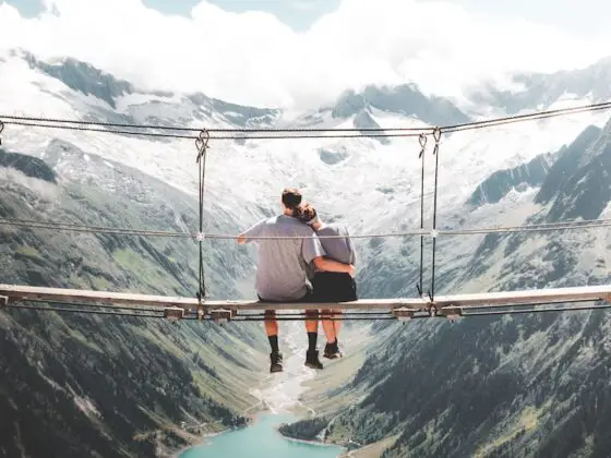 wochenendtrip zu zweit - minimoon - man and woman sitting on hanging bridge at daytime