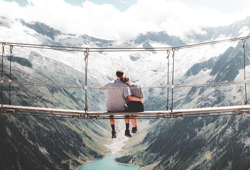 wochenendtrip zu zweit - minimoon - man and woman sitting on hanging bridge at daytime