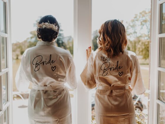 two bridesmaids in robes looking out a window - Trauzeuge Aufgaben